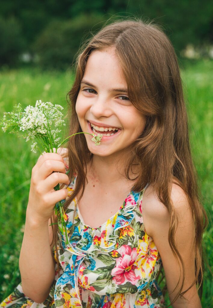 teenage girl with a flower on the grass smiles